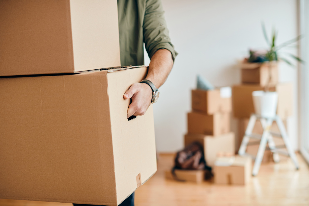 closeup-of-man-carrying-cardboard-boxes-while-relocating-into-new-apartment.jpg